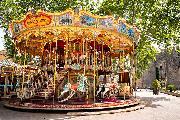 Aigues-Mortes, France - June 28, 2024: Carousel outside the main entrance to the fortified rampart walls of the town with tourists in the distance