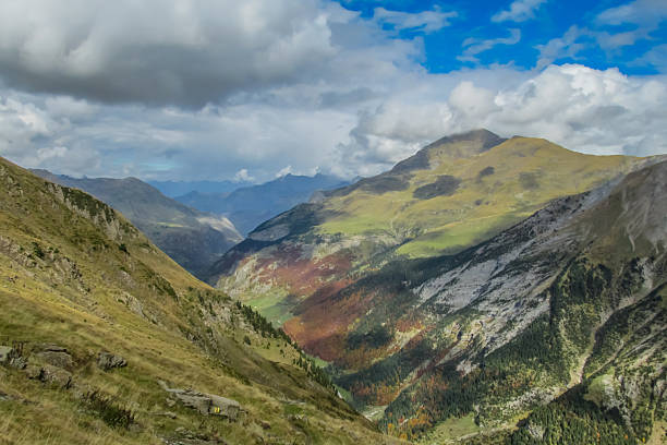 Pyrenees mountains in autumn with forested slopes, colorful foliage, and rugged peaks under clear sky. High altitude landscape showing seasonal vegetation, European mountain terrain, outdoor hiking environment, natural scenery, and panoramic wilderness background