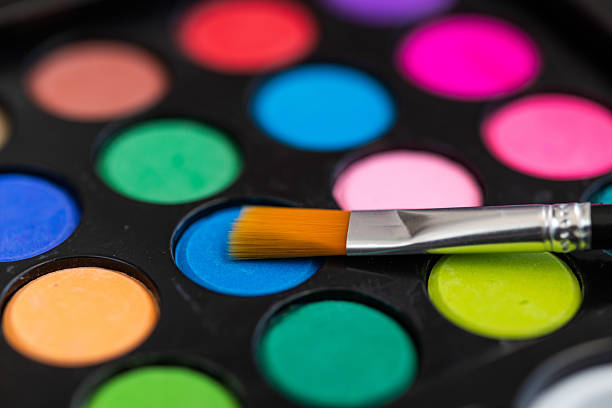 Professional makeup brush and set of eye shadows, on black isolated background. View from above.  Colorful back ground.