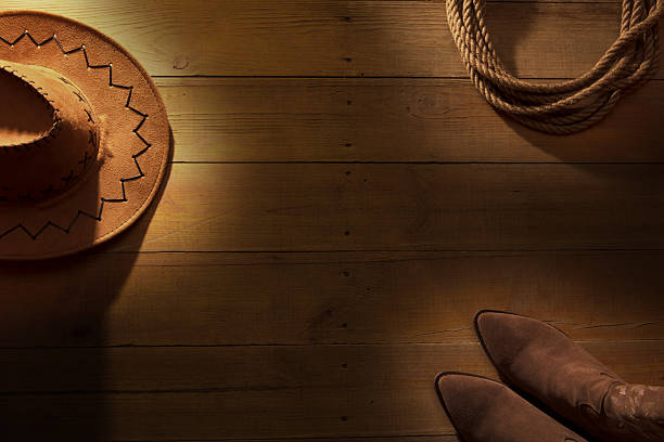Lasso, cowboy hat and boots on barn wood texture background. American wild west concept. Space for copy.
