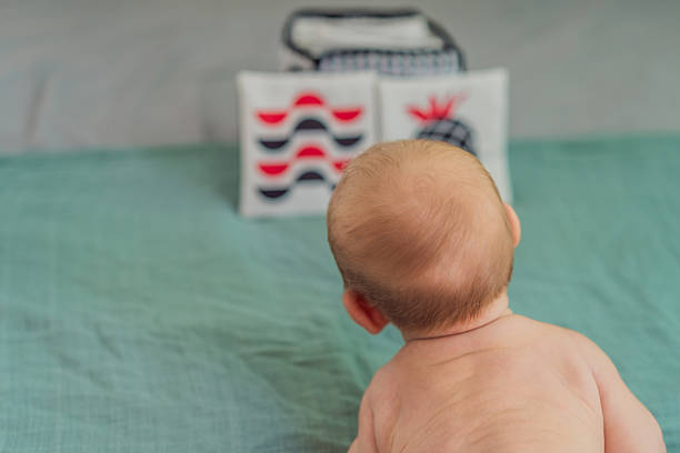 Newborn baby looking at black, white, and red high-contrast cards. Early visual stimulation for infant development. Concept of baby sensory learning and cognitive growth.