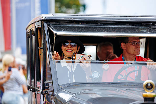Velden, Austria - August 30, 2025: Woman in stylish hat and sunglasses enjoys vintage car ride at Oldtimer Festival, capturing the essence of classic automotive celebration