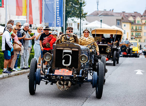 Velden, Austria - August 30, 2025: Classic vintage cars are showcased in a lively parade during the Oldtimer Festival with excited spectators along the street