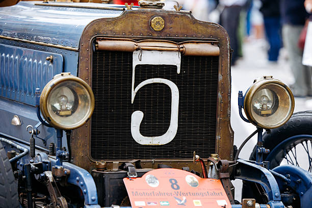 Velden, Austria - August 30, 2025: Vintage blue car featuring number 5 on the front, displayed at an Oldtimer Festival with excited crowd in the background