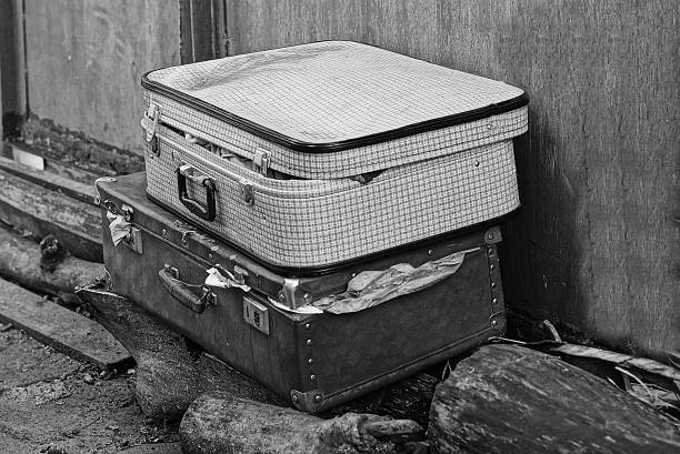 two big old closed white black dirty suitcases lie in the street
