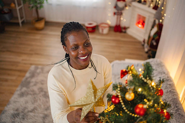 istock Woman smiling placing star on Christmas tree 2255452205