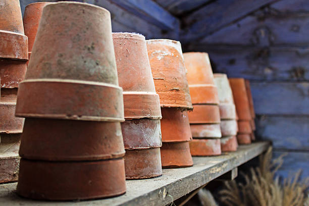 Essential gardening tools and supplies displayed with terracotta pots, a trowel, cultivator, metal watering can, and jute twine for potting plants and garden care.