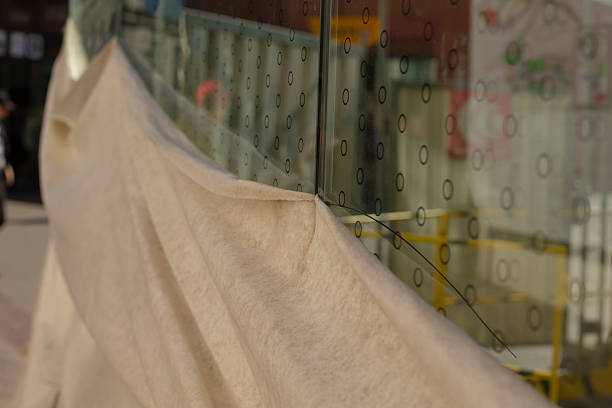 A sizable piece of fabric is draped over a glass wall, creating a fascinating contrast between the intricate material and the transparent surface
