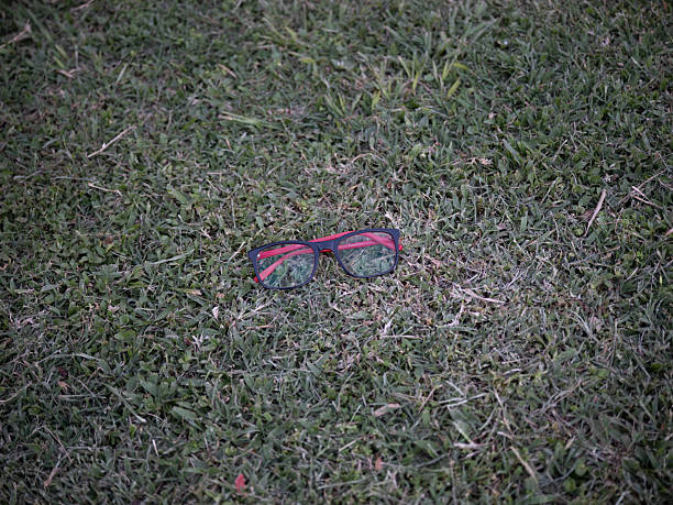 Eyeglasses resting on green grass in an outdoor environment. Suitable for concepts related to vision care, personal accessories, lifestyle, or everyday objects.