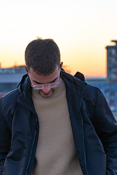 Young man standing on the rooftop against the cityscape at dusk
