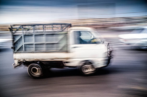 A white truck speeds along Avenue Hassan II in Rabat, Morocco. The panning shot emphasizes the motion and bustling urban atmosphere.