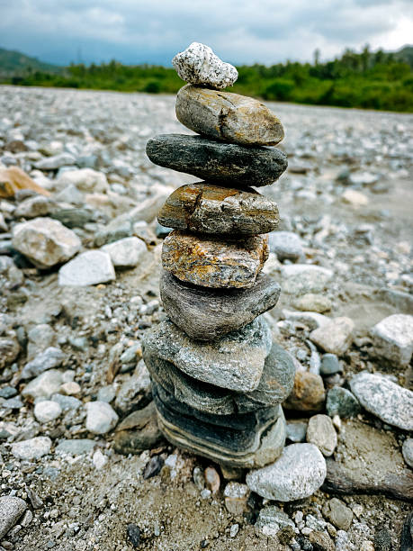 A balanced stack of river stones arranged in a playful structure resembling a classic stone stacking game. The close up view highlights natural textures, earthy tones, and the concept of balance and simplicity