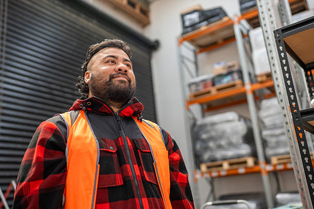 Portrait of a Pacific Islander male worker standing inside a warehouse with industrial shelving in background