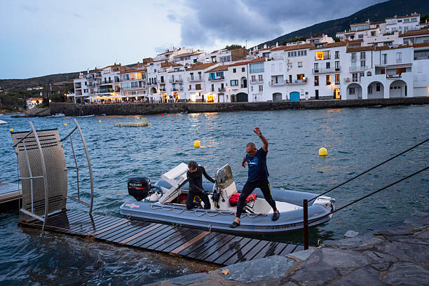 Cadaques, Spain - July 5, 2024:  Local fishermen jump onto a slippery dock during a stormy incoming tide in the Mediterranean Sea in the picturesque fishing village of Cadaques, Costa Brava, Catalonia, SpainSpain