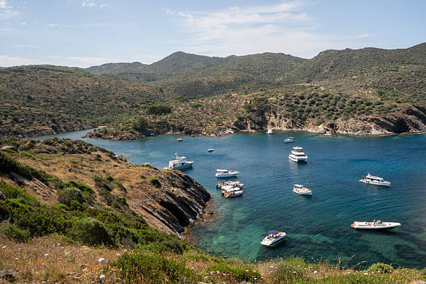 Port lligat, Spain - July 5, 2024: Distant view of tourists relaxing on yachts in the Mediterranean Sea in the Cap de Creus Natural Park along the rocky Costa Brava, the easternmost point of Catalonia Spain near Cadaques, Girona