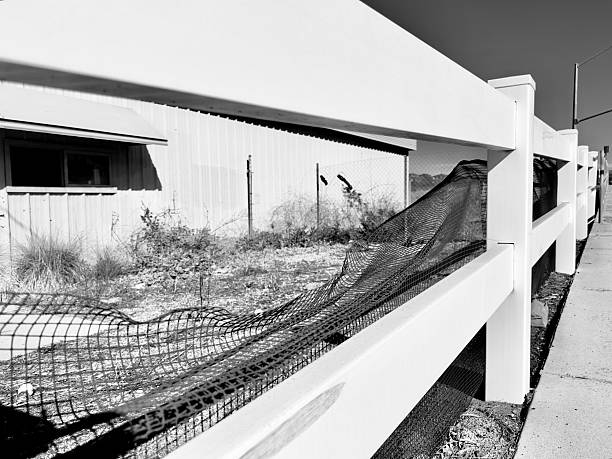 A black and white architectural shot of a security fence surrounding a vacant building in San Marcos, CA.