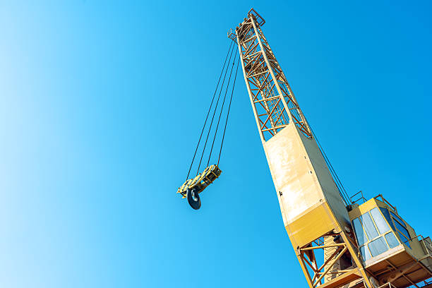 Industrial crane boom and hook against a sunny blue sky