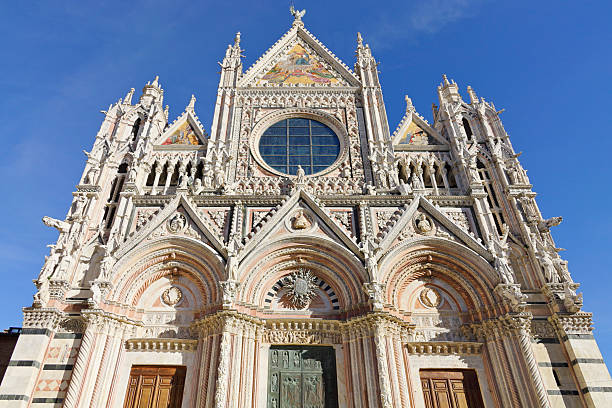 The front facade of Siena Cathedral (Duomo di Siena) in Siena, Tuscany, Italy. Built between the 12th and 14th centuries, the cathedral reflects a distinctive blend of Romanesque and Gothic architecture and remains a central landmark of the city’s historic center.