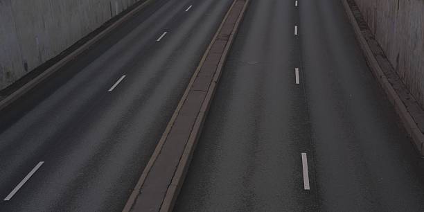 Empty road with lane markings and concrete walls on both sides. City streets, empty freeway in evening or night time.