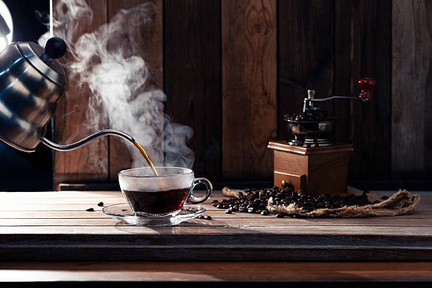 istock Pour black coffee into a coffee cup There are roasted coffee beans on the table. with a black background and dark colors 2255502447