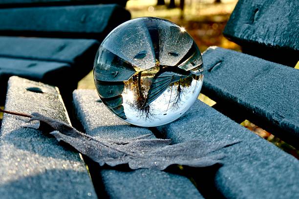 Crystal ball on frozen bench in park during autumn