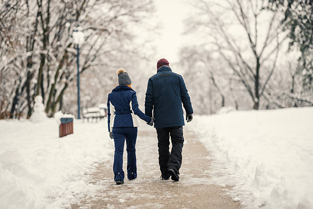 istock Couple holding hands walking along snow covered park path 2255502905
