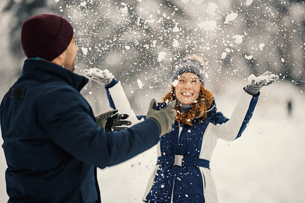 family having fun in winter, throwing snow up in blue sky.