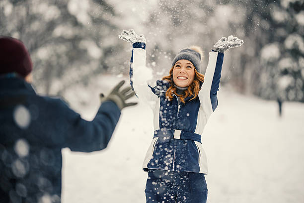 Group of millenial young adult friends throwing snowballs in wintertime in a snow filled park