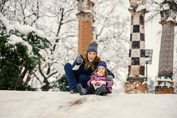 Happy little girl sliding down the hill on saucer sled. Girl enjoying slider ride on the snow.