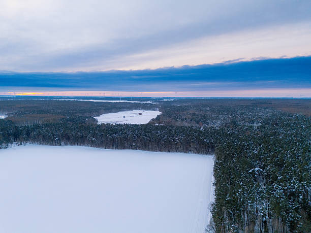 Early morning landscape with the rising sun lighting the forest, fields and lake