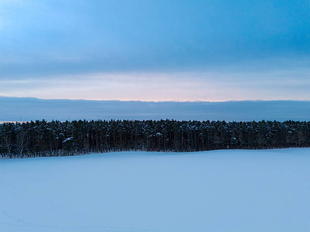 Early morning landscape with the rising sun lighting the forest, fields and lake