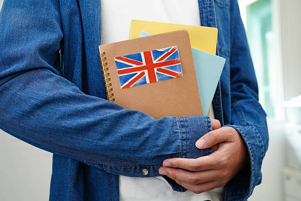 Learning English, Asian teenage student holding book with flag for language program education.