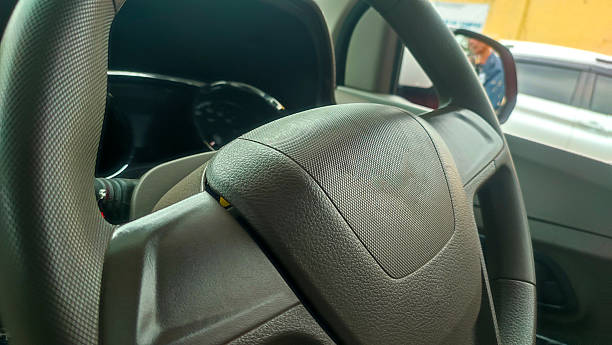 Close-up view of a car steering wheel with dashboard details visible in the background. Automotive interior and driving control concept.