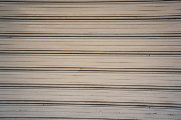 Texture background shows Closed Rolling shutters in front of closed store fronts.