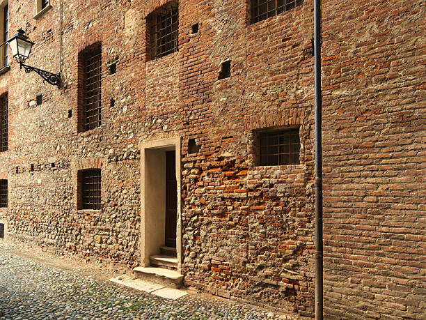 Brick facade of a building with windows and grates, Cuneo