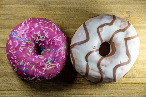 A delightful pair of colorful glazed donuts on a wooden surface