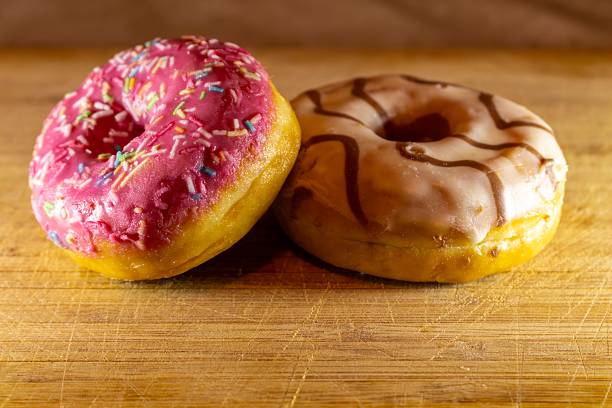 A delightful pair of freshly baked donuts on a wooden surface
