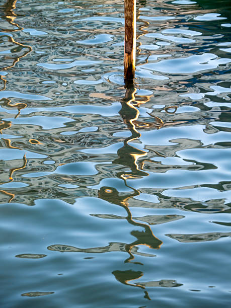 A wooden pole, water, sun, and reflections as abstract artists. Taken in the canals of Venice.