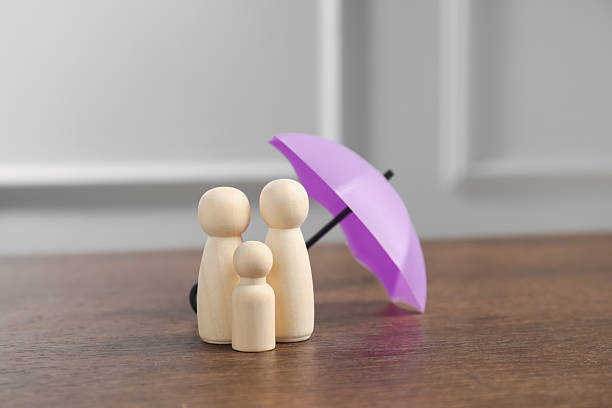 istock Human figures under umbrella on wooden table. Insurance concept 2255533752
