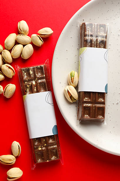 Delicious Dubai chocolate bars and pistachios on red background, flat lay