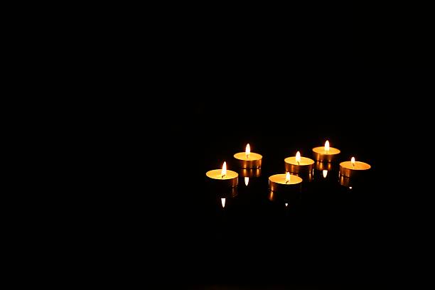 Many burning candles in darkness, space for text