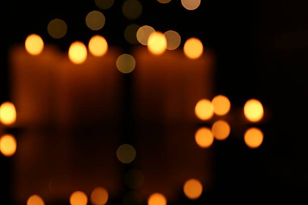 A lit candle with a bright, flickering flame stands against a subtly blurred indoor background. The warm light provides a sense of comfort, tranquility, and timeless beauty.