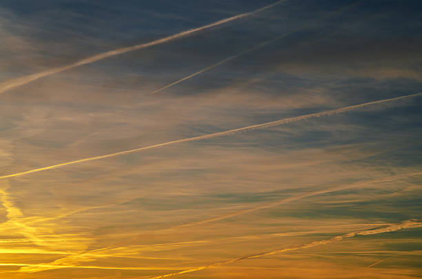 Sunset sky with contrails creating abstract patterns across the horizon