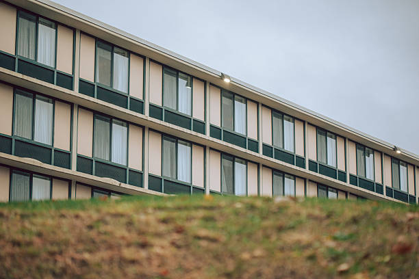 Ground view angle of several rows of motel room windows on a rainy day creates a moody scene.