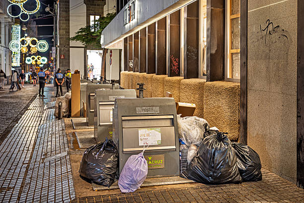 Santa Cruz, Tenerife, Spain, Europe - December 15th 2025: A group of waste‑sorting containers stands on the street, filled beyond capacity, with additional garbage left beside them by residents. The scene documents local waste‑management conditions and the visible overflow around the public recycling area.