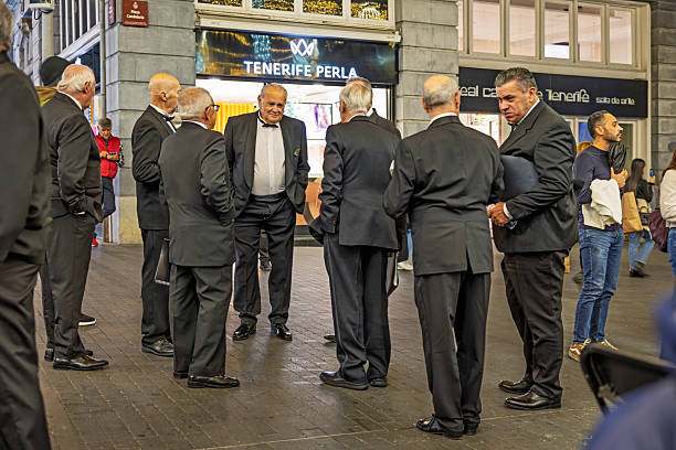 Santa Cruz, Tenerife, Spain, Europe - December 18th 2025: A group of middle‑aged men dressed in suits relax together while waiting to perform with their choir.