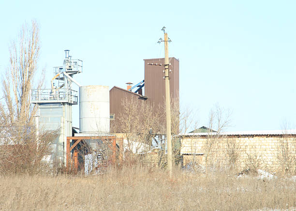 A large factory with a large tower. Outdoor. Grass. Sky. Building. Factory