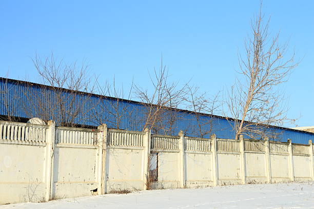 A white fence in a snowy area. Outdoor. Sky. Building. Architecture. Day
