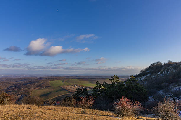 istock Winter view from Palava hills to the valley with fields and forests under a blue sky with moon. Sunny day in South Moravia, Czechia 2255554176