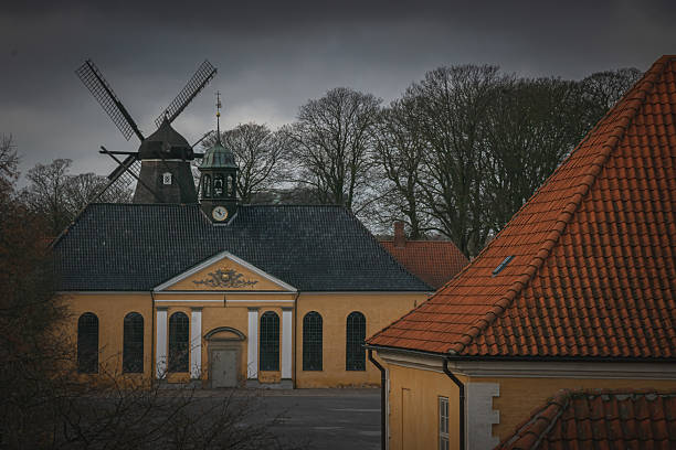 Traditional Danish architecture with windmill and flag on cloudy winter day